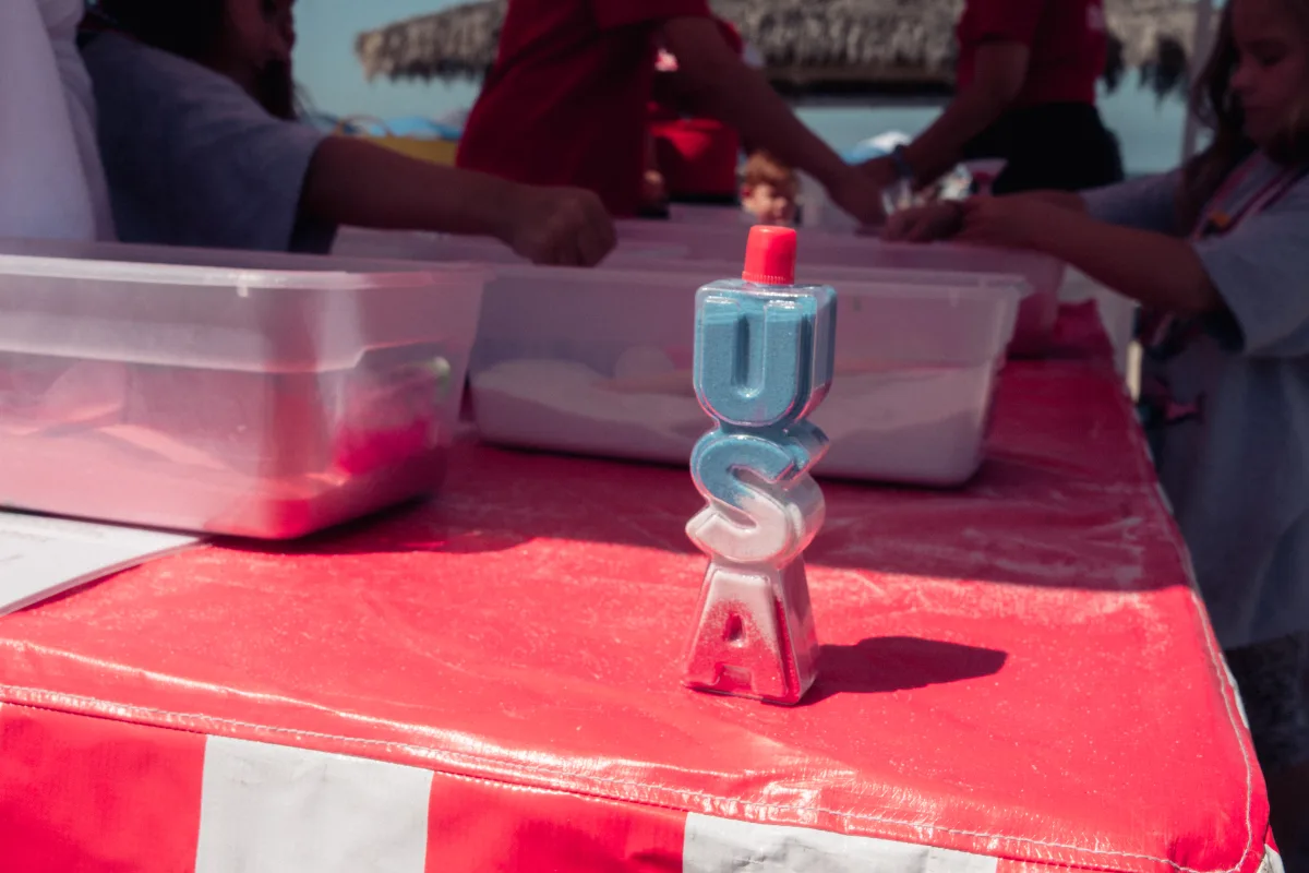 A red, white and blue sand-art craft station set up on a table at an outdoor summer event
